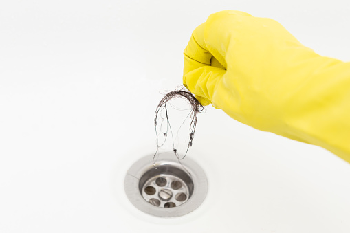 Cleaning hair from drain while wearing cleaning gloves