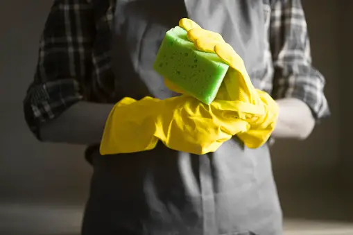 Wearing cleaning gloves and holding sponge