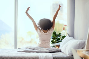 Woman sitting on her bed stretching in the morning