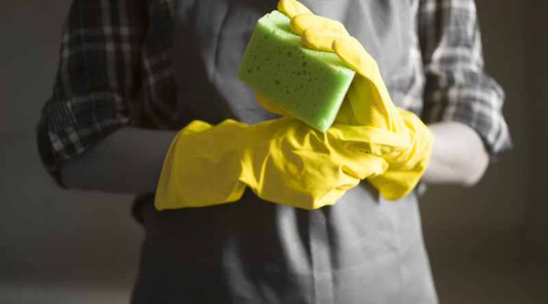 Wearing cleaning gloves and holding sponge