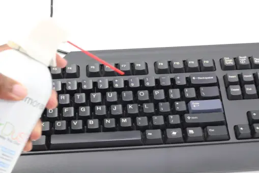 Hand holding compressed air and cleaning keyboard