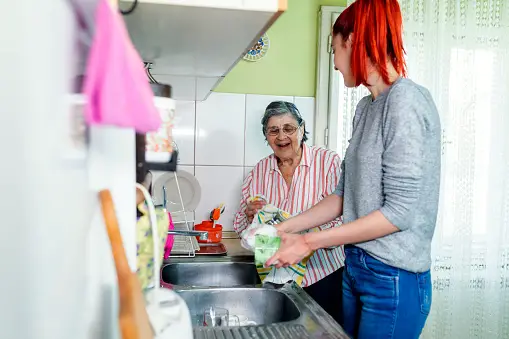 Older woman getting housework assistance in the kitchen from a younger woman