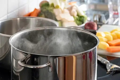 Pots on stove and vegetables laid out for cooking in bulk