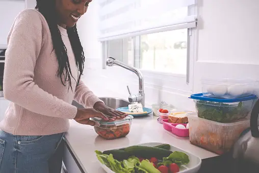 A woman packing leftovers into plastic containers