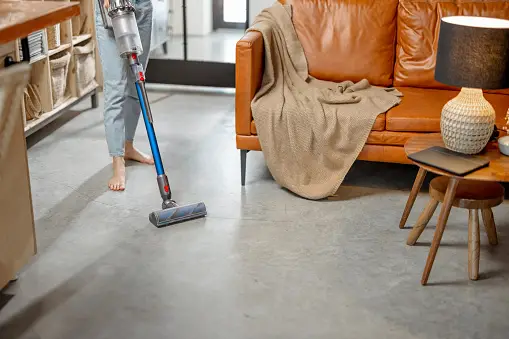 Woman cleaning carpet of home with cordless vacuum