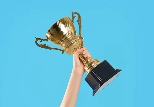 Woman's hand holding a gold trophy