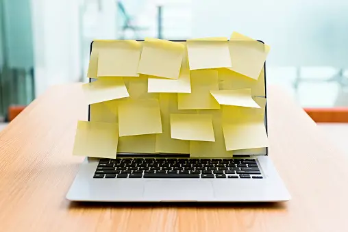 Laptop with screen covered in yellow sticky notes
