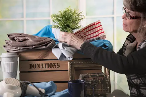 Older lady placing items into a donation box
