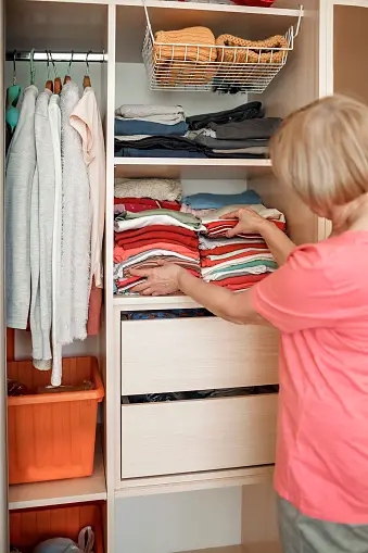 Older woman sorting clothes in closet