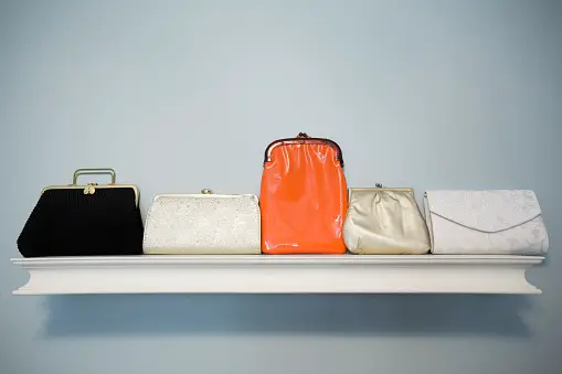 Various purses lined up on a white floating shelf