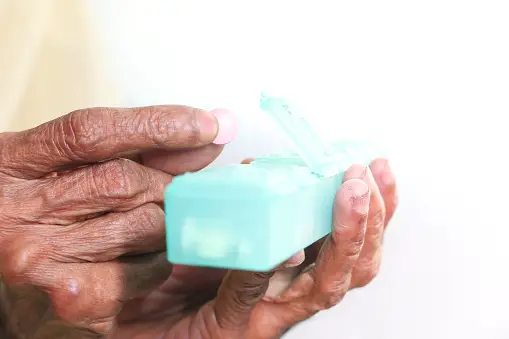Senior woman's hands holding pill separator container