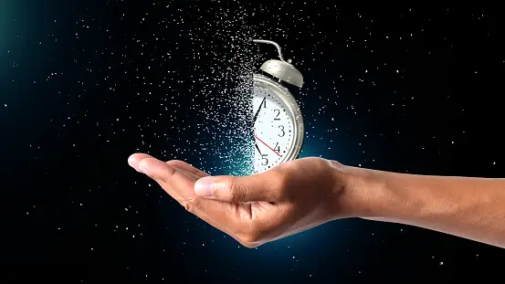 Woman holding clock in her hand with one side of the clock in shadows