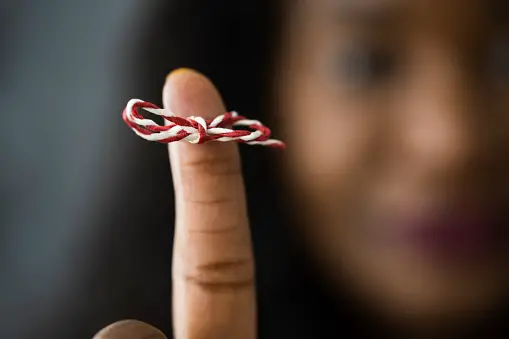 Woman holding up finger with memory string on it