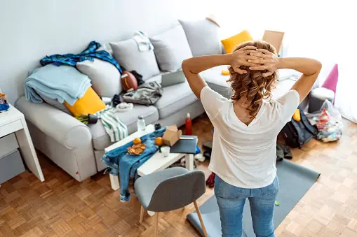 Rear view of woman holding hands on her head as though in shock about messy home