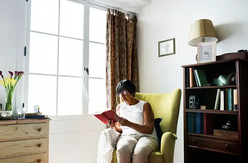 Older woman sitting in a comfortable chair reading a book