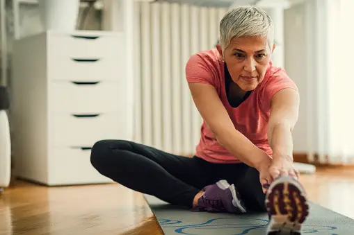 Older woman stretching on mat in home gym