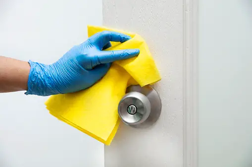 gloved hand wiping down doorknob