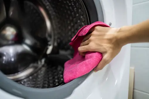 Hand holding cloth to clean washing machine